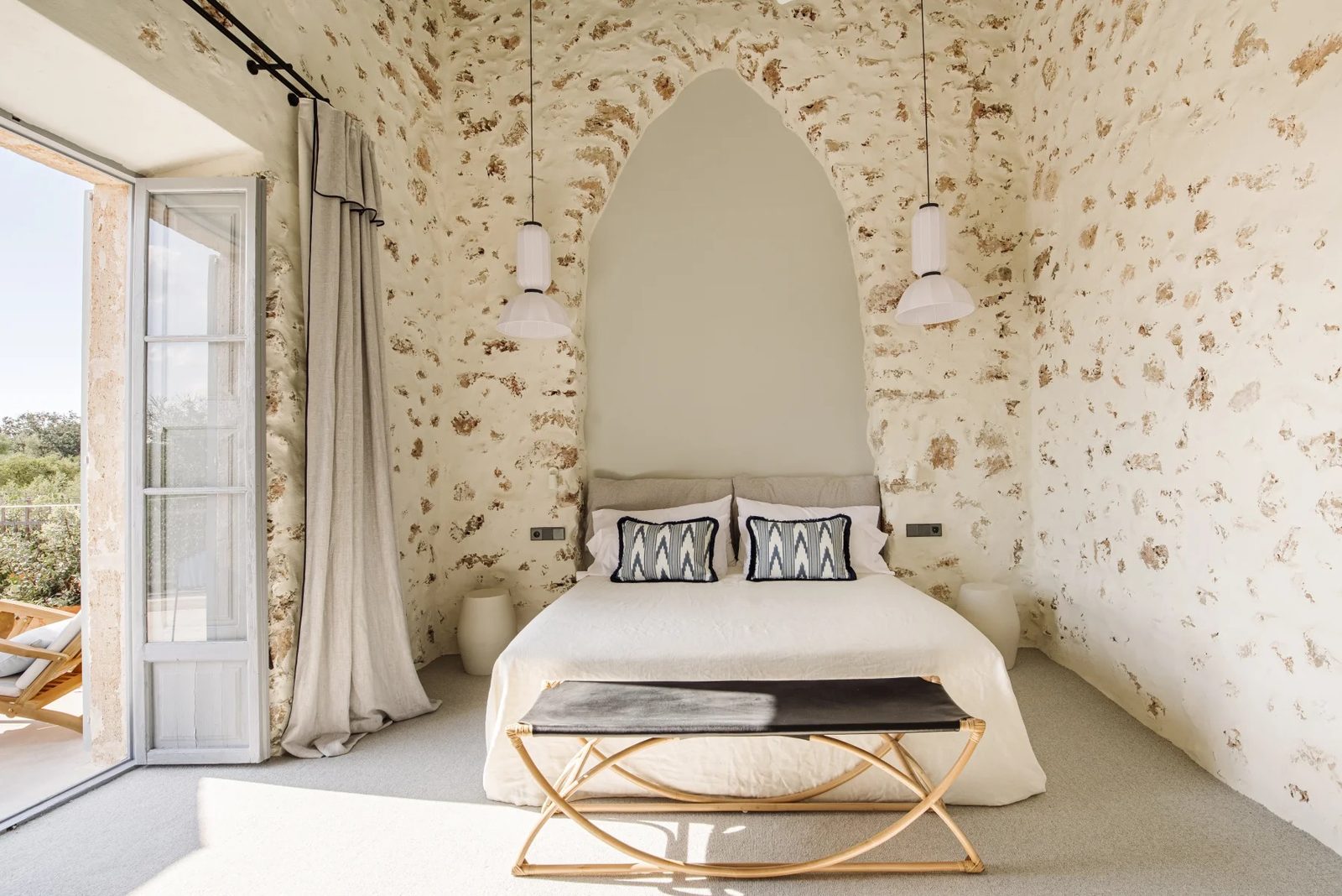 Junior suite bedroom with exposed stone walls and a pointed arch niche behind the bed