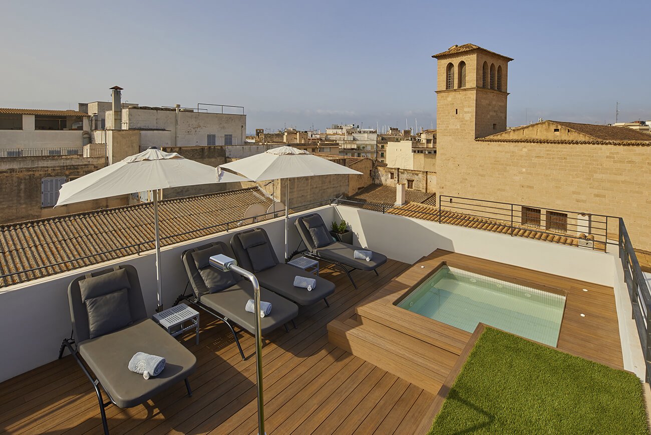 Rooftop terrace with sun loungers, parasols and a small pool above Palma's old-town roofs