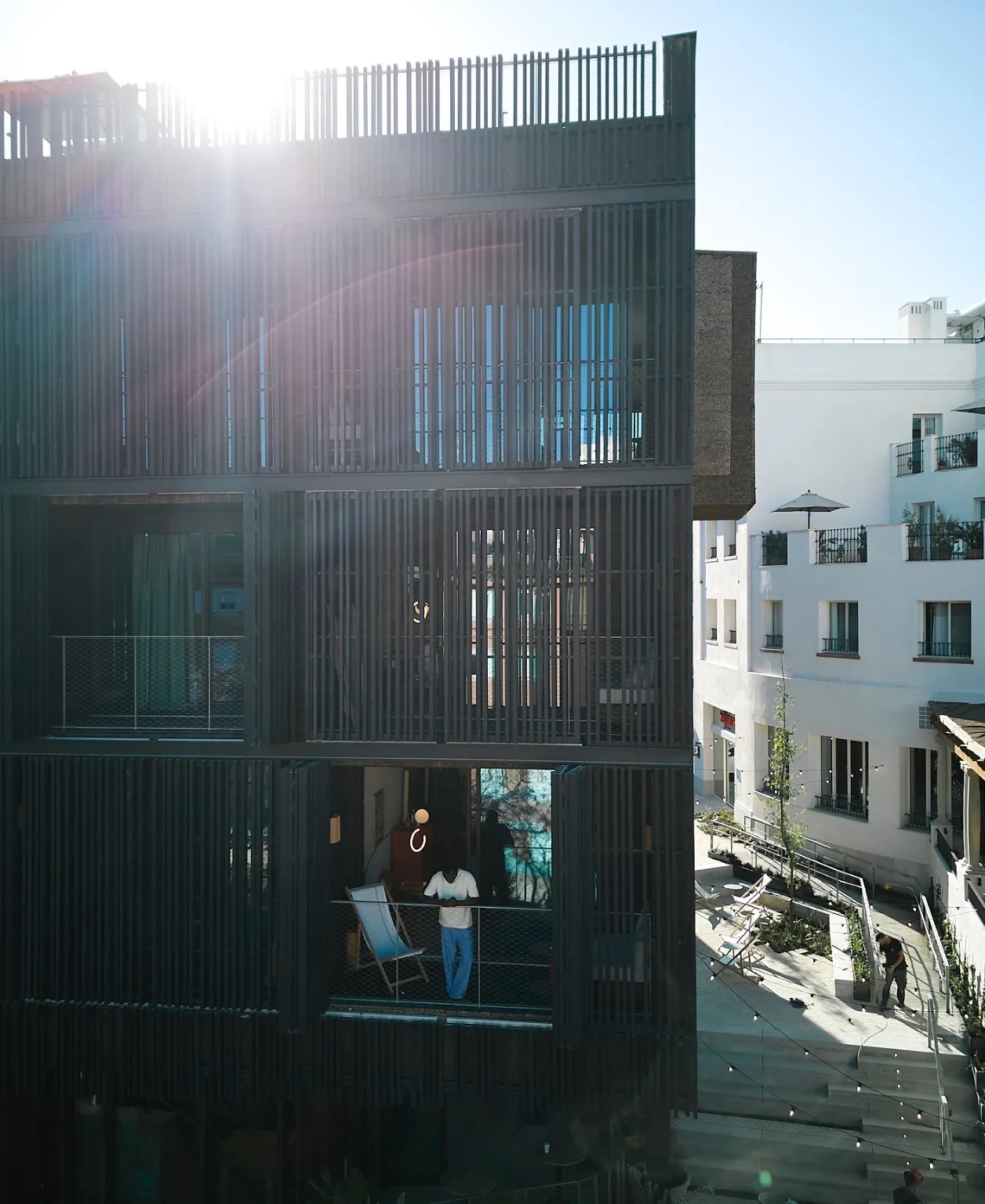 Exterior of the new Passivhaus wing, its vertical wood-slat facade lit by late-afternoon sun above the El Terreno street