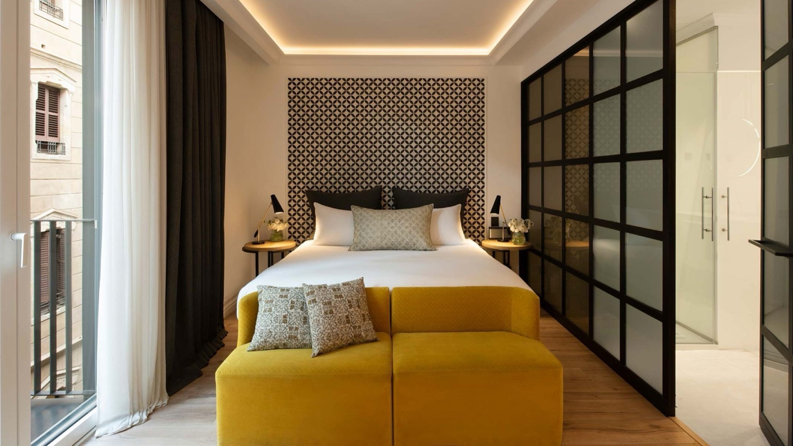 Bedroom with a patterned headboard and a glass-paneled bathroom divider
