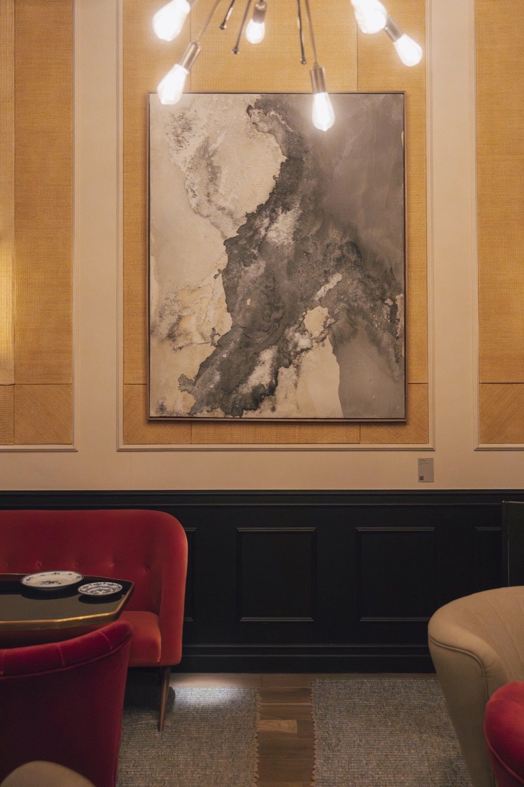Lounge with red velvet armchairs and a large abstract painting