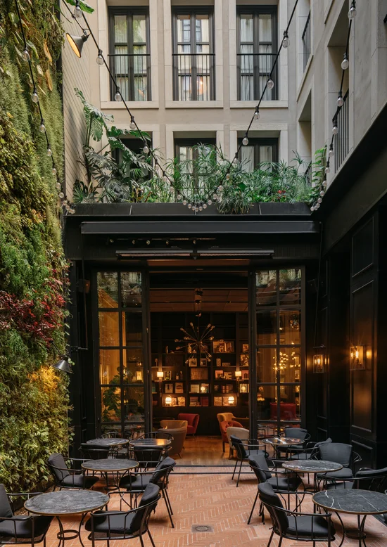 Interior courtyard terrace with bistro tables, string lights and a vertical garden wall