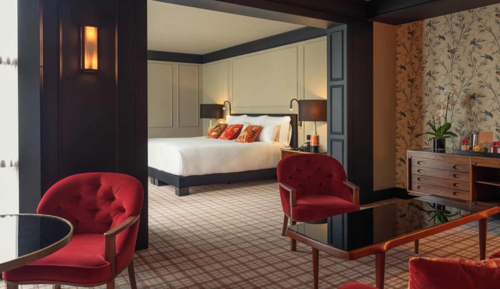Suite with red armchairs, a black coffee table and a view through to the bedroom