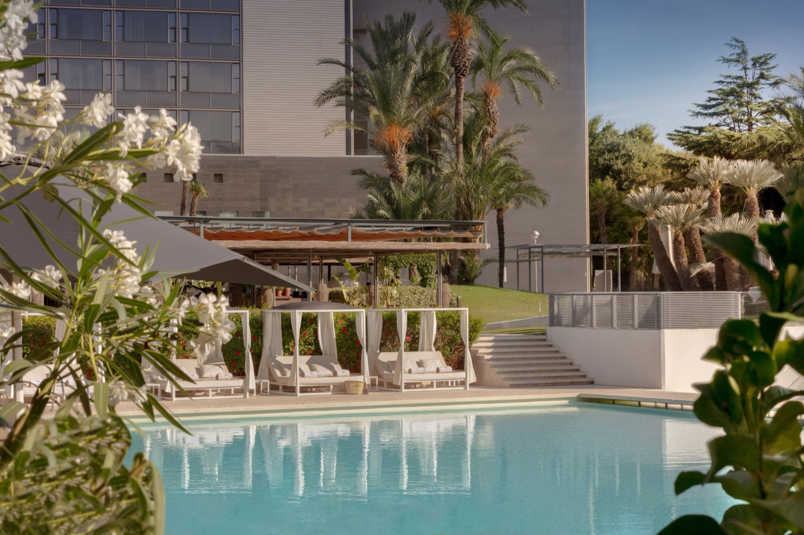 Outdoor pool with white cabanas and palm trees