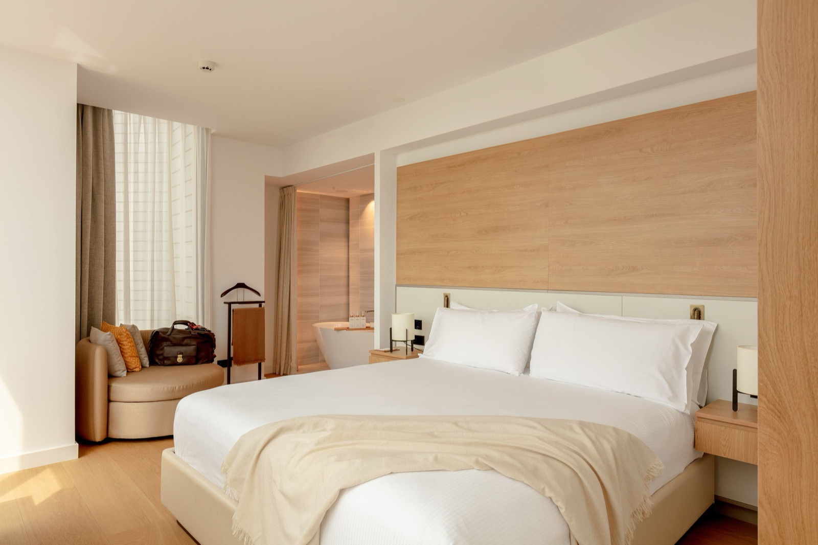 Room with a king bed, a wood-panel headboard and an open bathtub