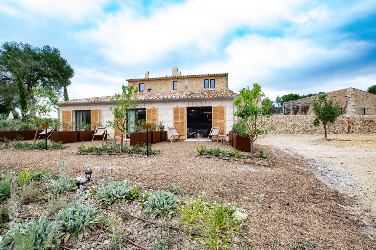 Stone farmhouse facade at Treurer with wooden shutters, deck chairs, and a gravel garden path