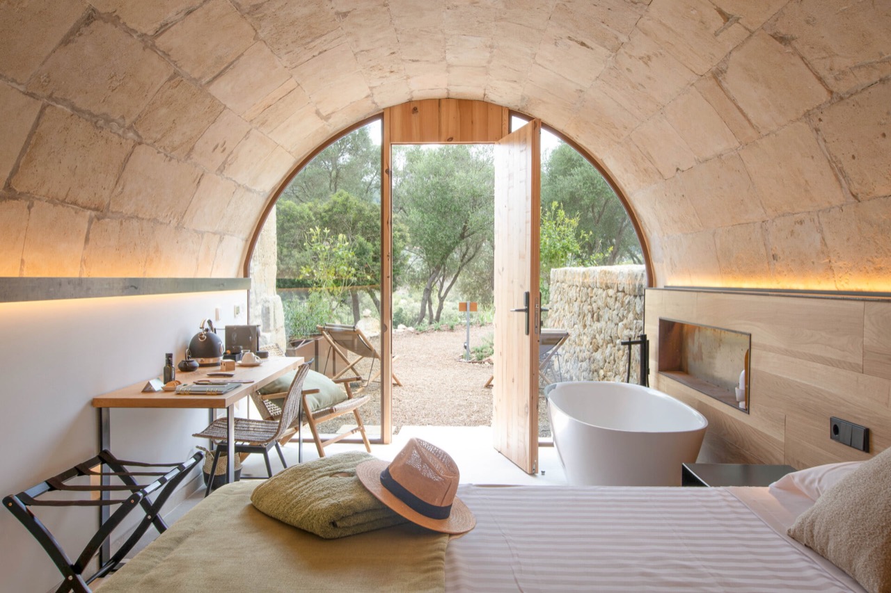Vaulted stone ceiling room at Treurer with a freestanding bathtub and a door opening onto the olive grove