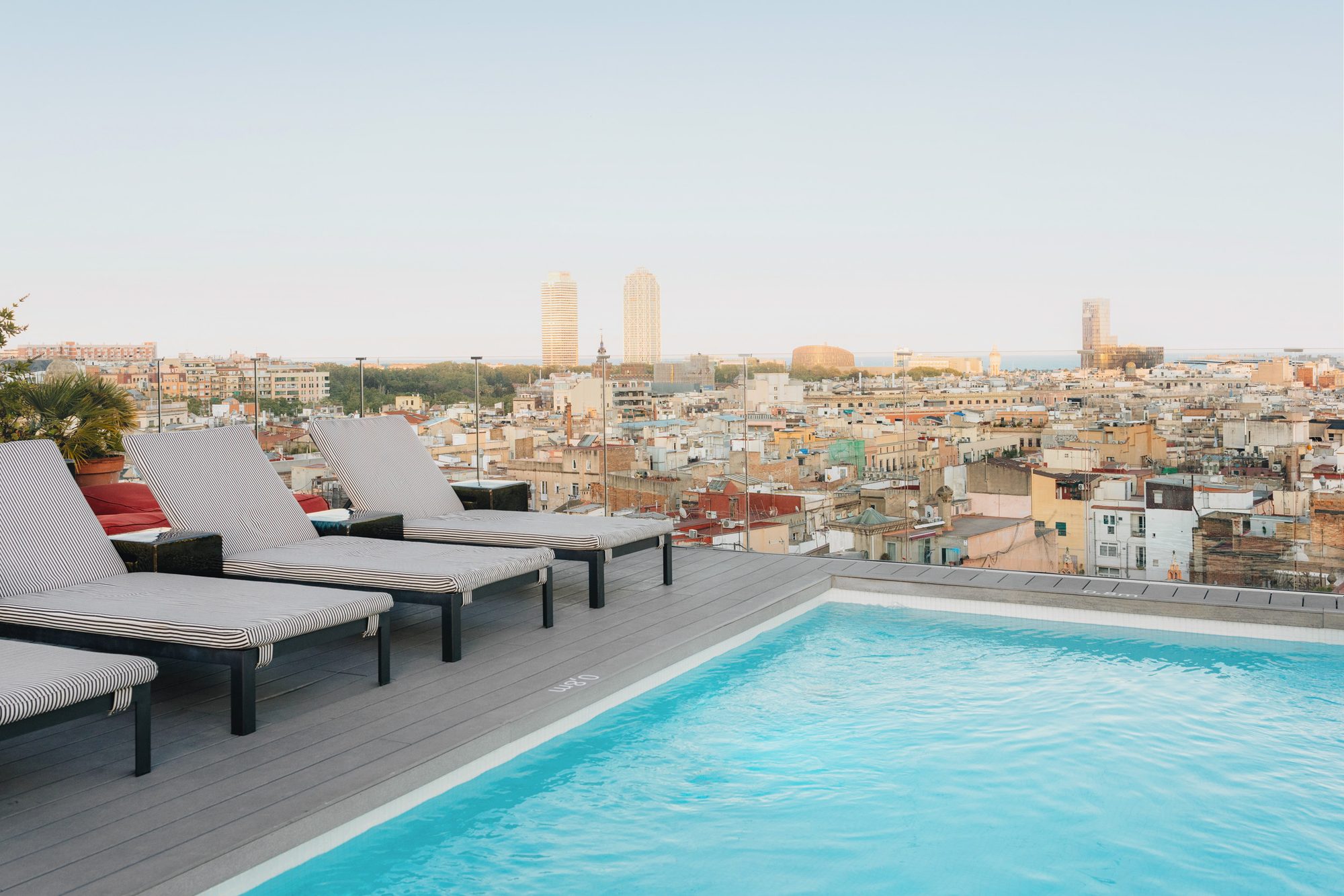 Rooftop pool at Uma House by Yurbban with striped loungers along the edge overlooking the Barcelona skyline