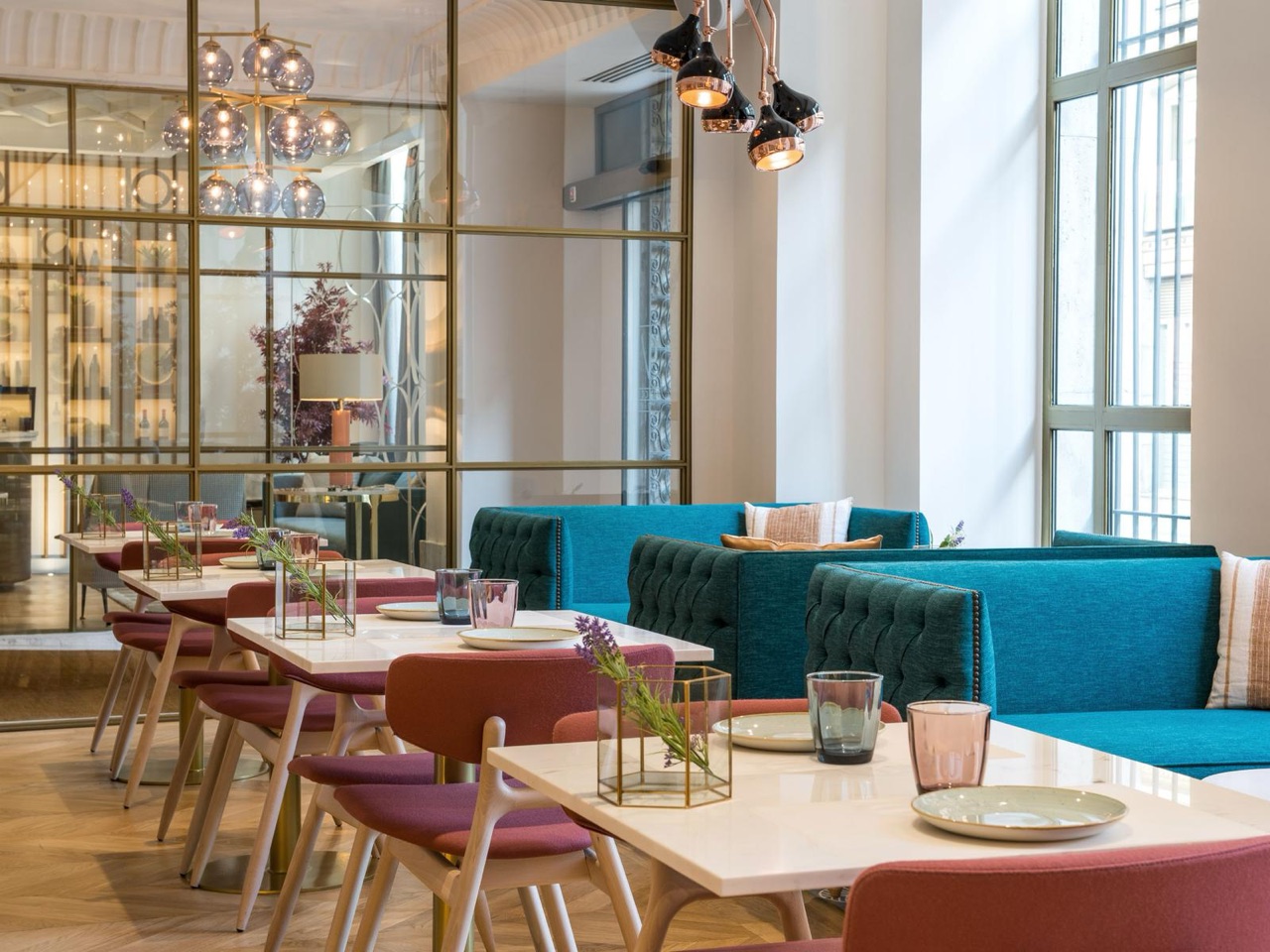 Bellini Food & Bar dining room with marble-topped tables, burgundy and teal upholstered seating, and a glass-partitioned wine display in the background.