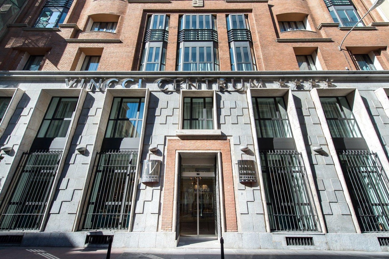 Stone and brick facade of Vincci Centrum with the hotel's name carved above the ground-floor windows and a glass entrance door at street level.