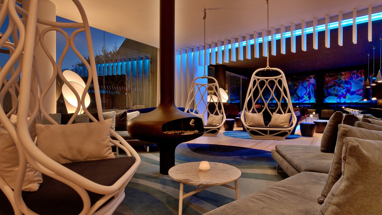 Hotel lounge bar with hanging rattan chairs and an illuminated ceiling