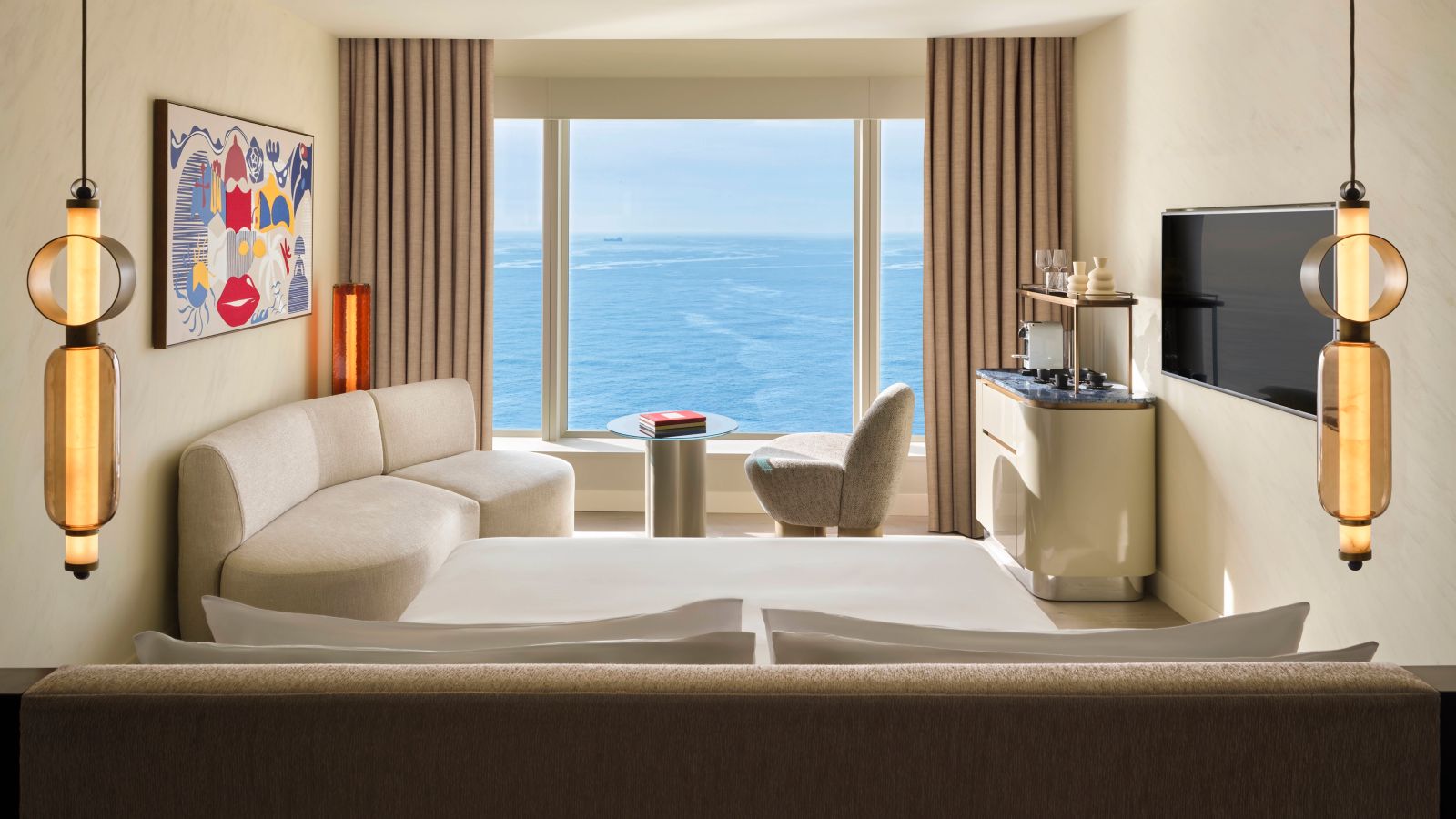 Guest room with a sea-view window, sofa and minibar console