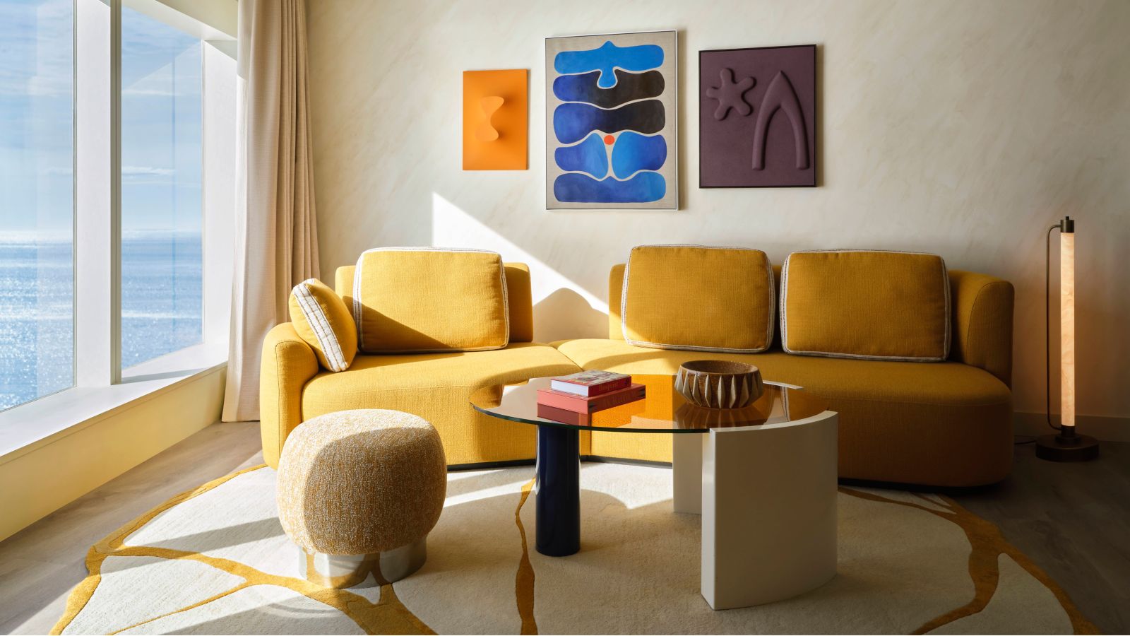 Suite living room with a yellow sofa and a floor-to-ceiling sea-view window