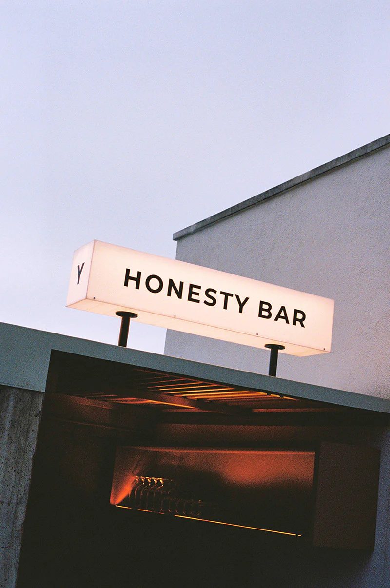 Illuminated "Honesty Bar" sign with the Yurbban Y logo mounted above an entrance at Yurbban Ramblas