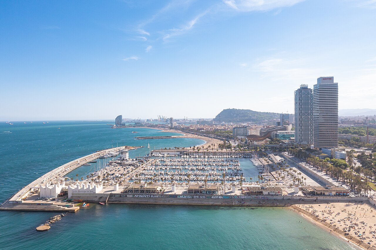 Aerial view of Port Olímpic's marina, twin towers and beach promenade in Barcelona