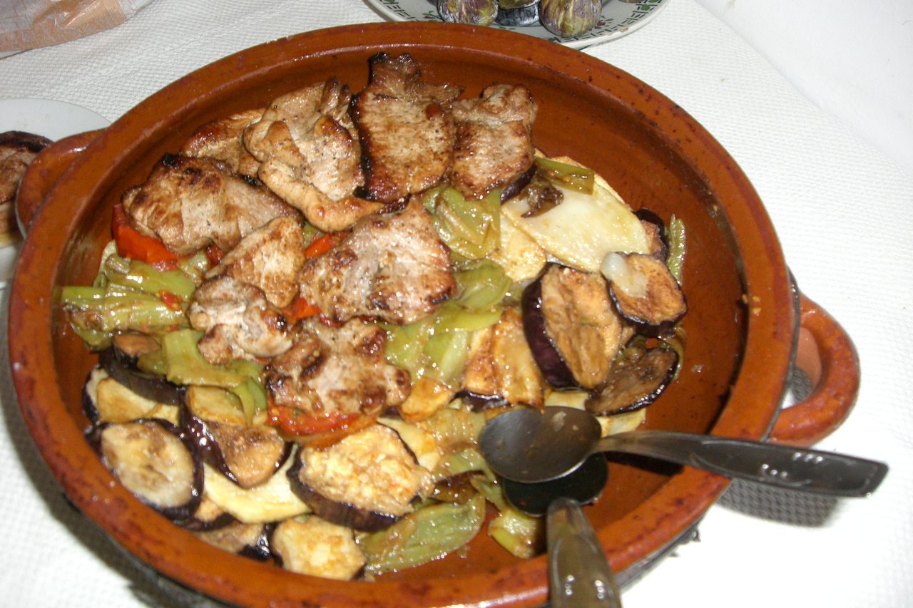Tumbet, the Mallorcan layered vegetable dish, topped with pork in a clay dish