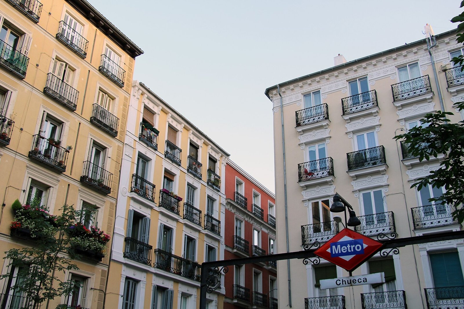 Apartment buildings with balconies around Plaza de Chueca in Madrid, with a red Metro sign.