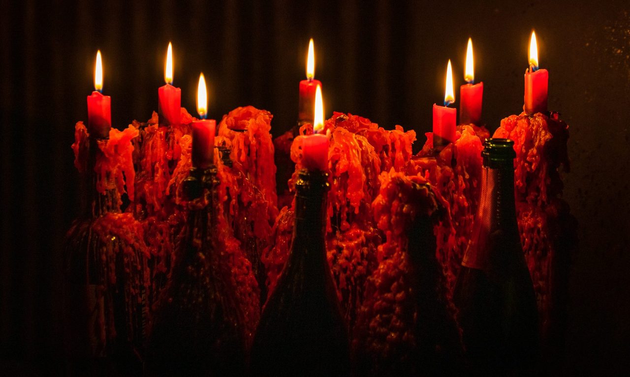Red candles dripping wax over wine bottles, from Clandestí's own website