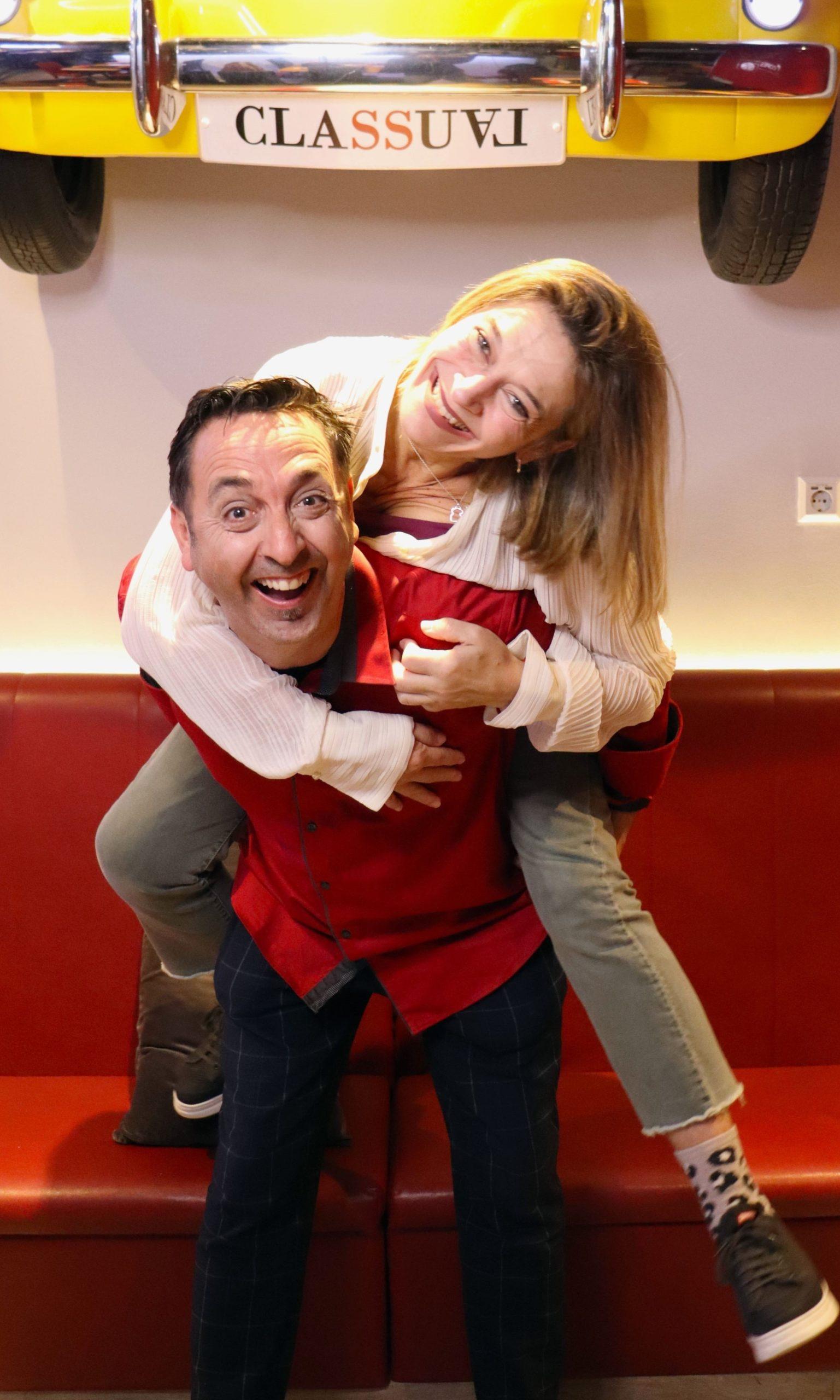 Santos and Sílvia Casas, owners of Espai Classual, laughing together inside the Badalona restaurant, with the restaurant's yellow car decor on the wall behind them