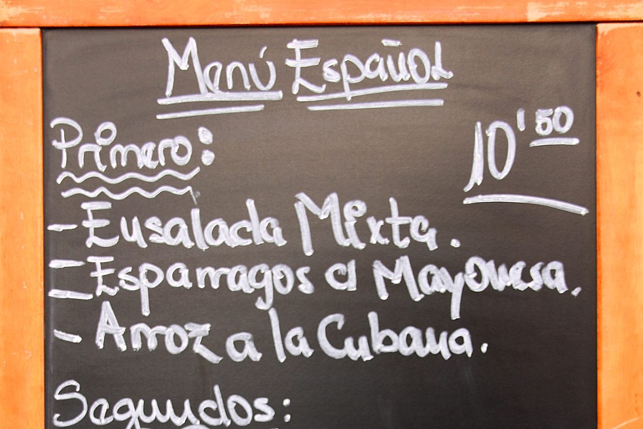 A chalkboard set menu outside a Spanish restaurant, listing the first courses