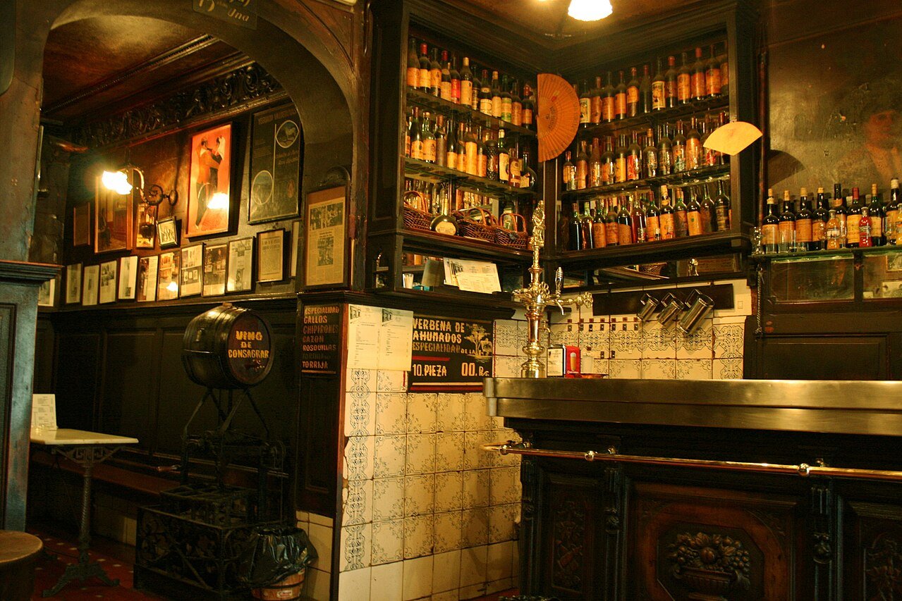 The carved wooden bar of Taberna de Antonio Sánchez, with tiled walls and shelves of bottles behind
