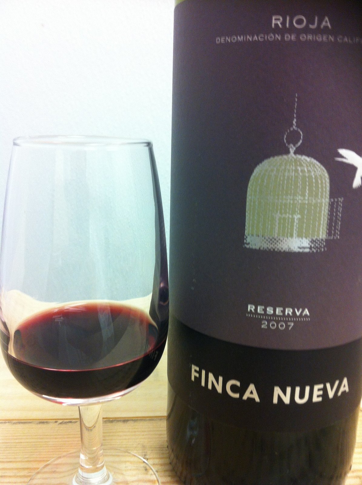 A glass of red wine beside a bottle of Rioja reserva.