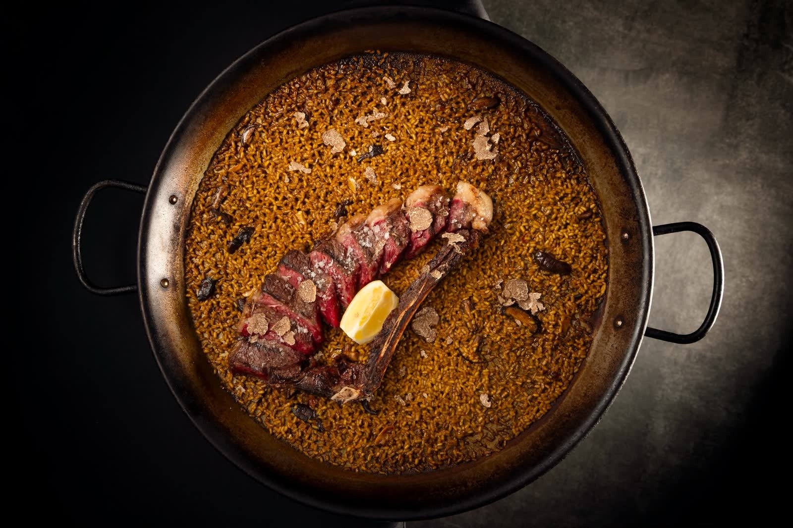 A pan of rice topped with slices of grilled meat, seen from above.
