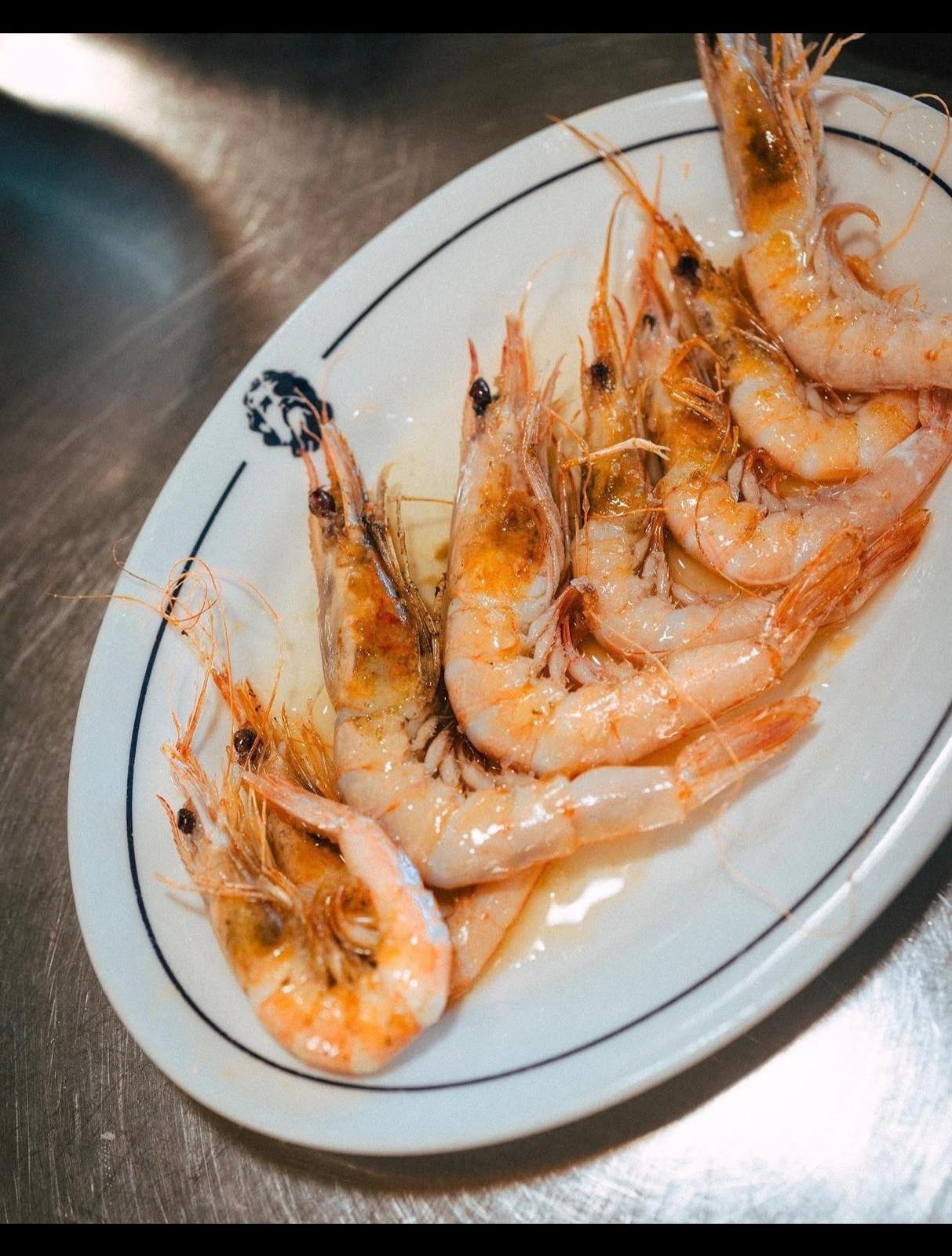 A plate of cooked prawns on a steel counter.