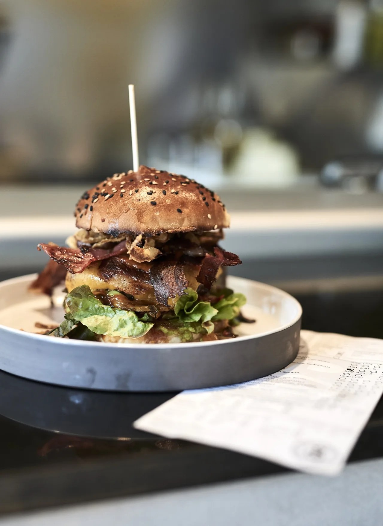 A stacked bacon cheeseburger on a plate at Badal Corner