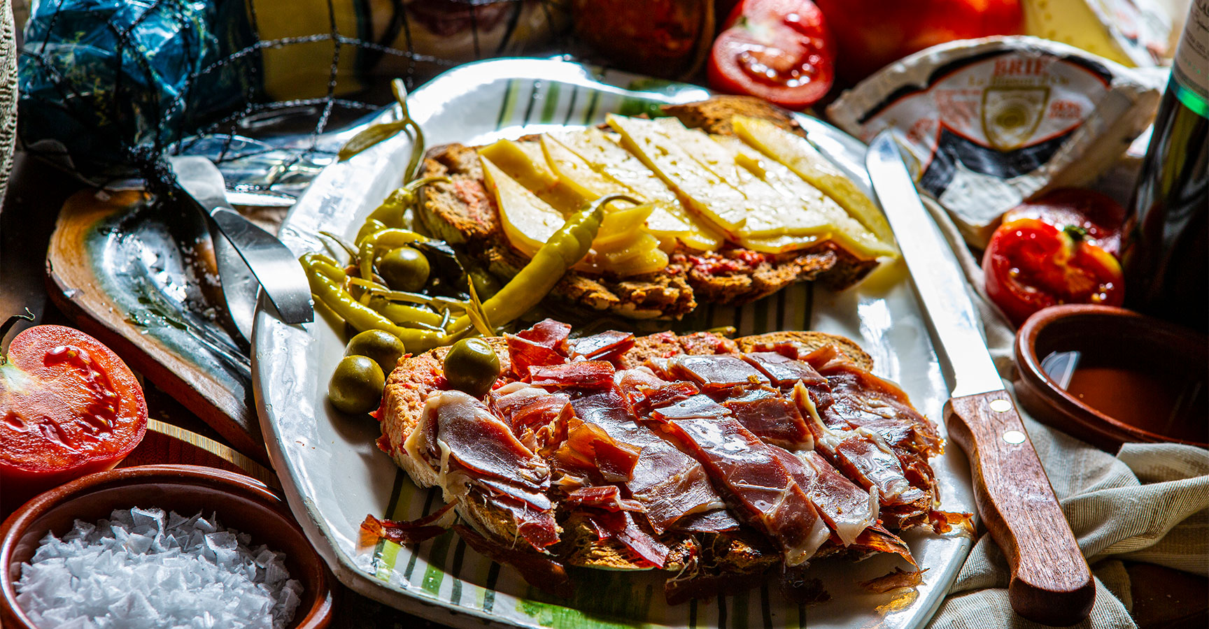 Pa amb oli topped with sliced jamón, cheese and olives