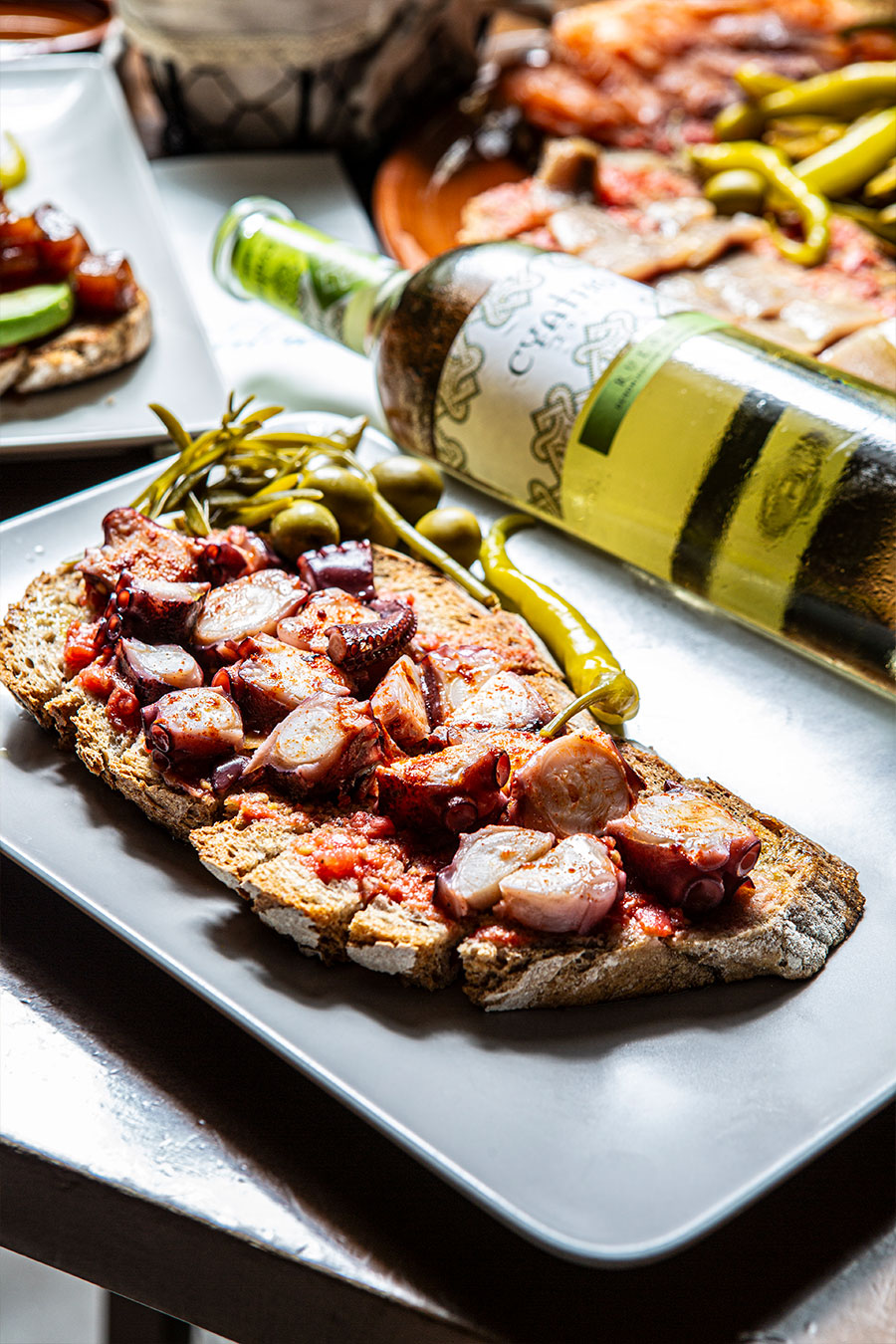 Octopus pa amb oli served beside a bottle of white wine