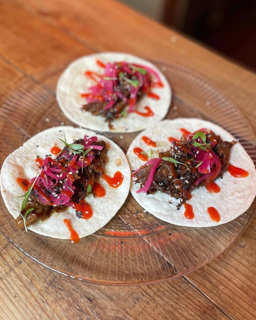 Three tacos with braised meat, pickled red onion and hot sauce at Bar Salvatge