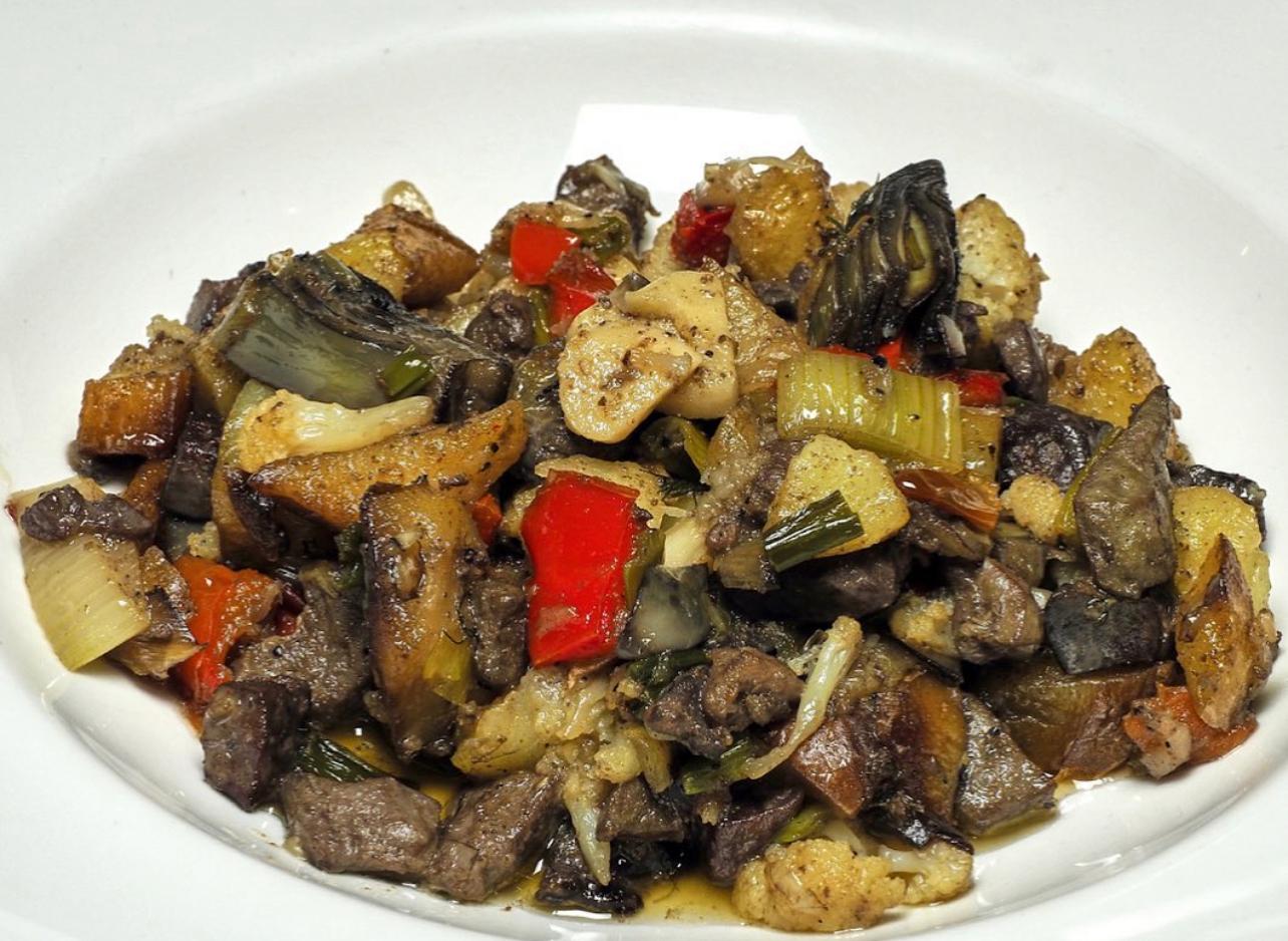 Frito mallorquín, diced fried offal and vegetables on a plate