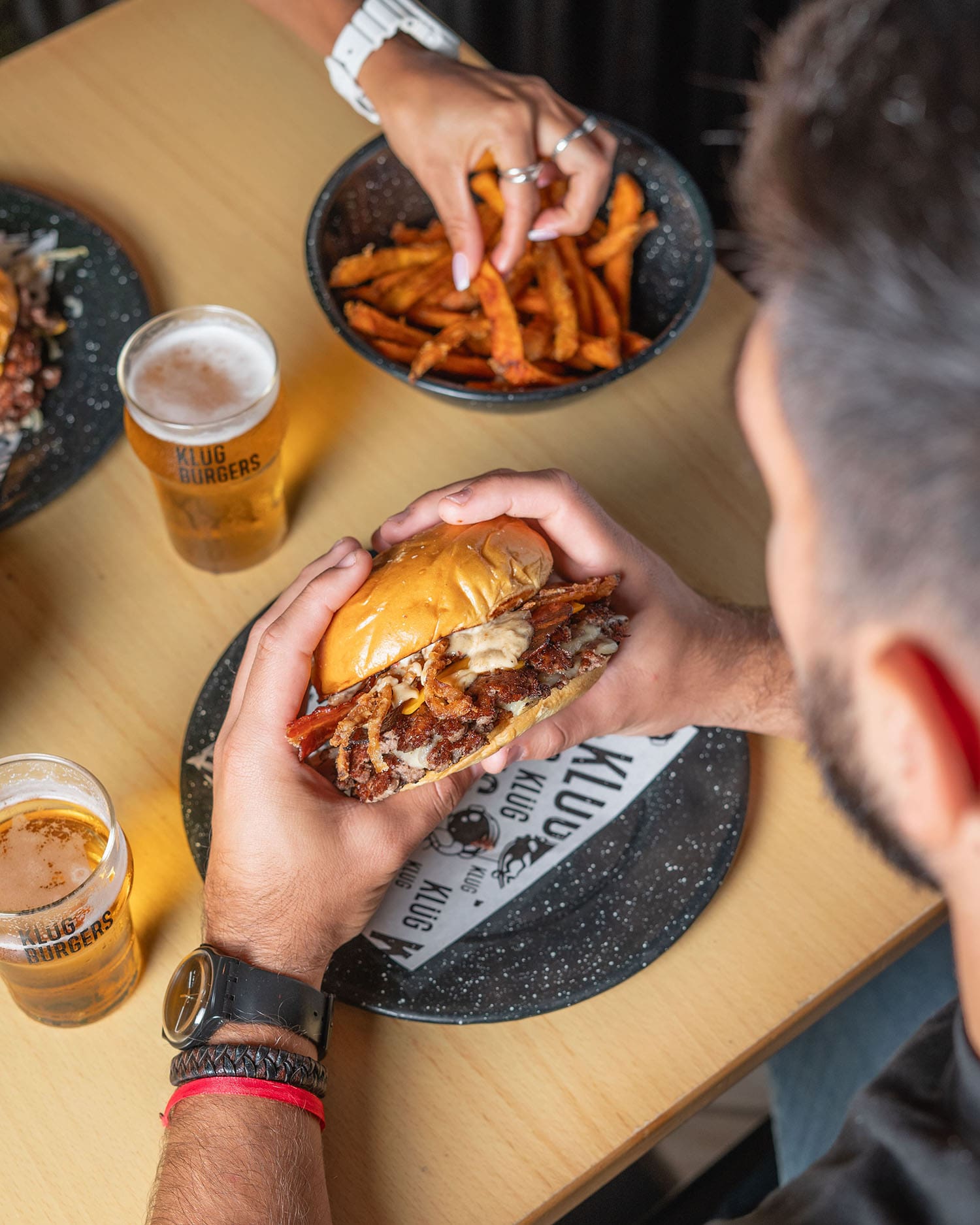 A smash burger with sweet potato fries and a glass of craft beer at Klüg Burgers
