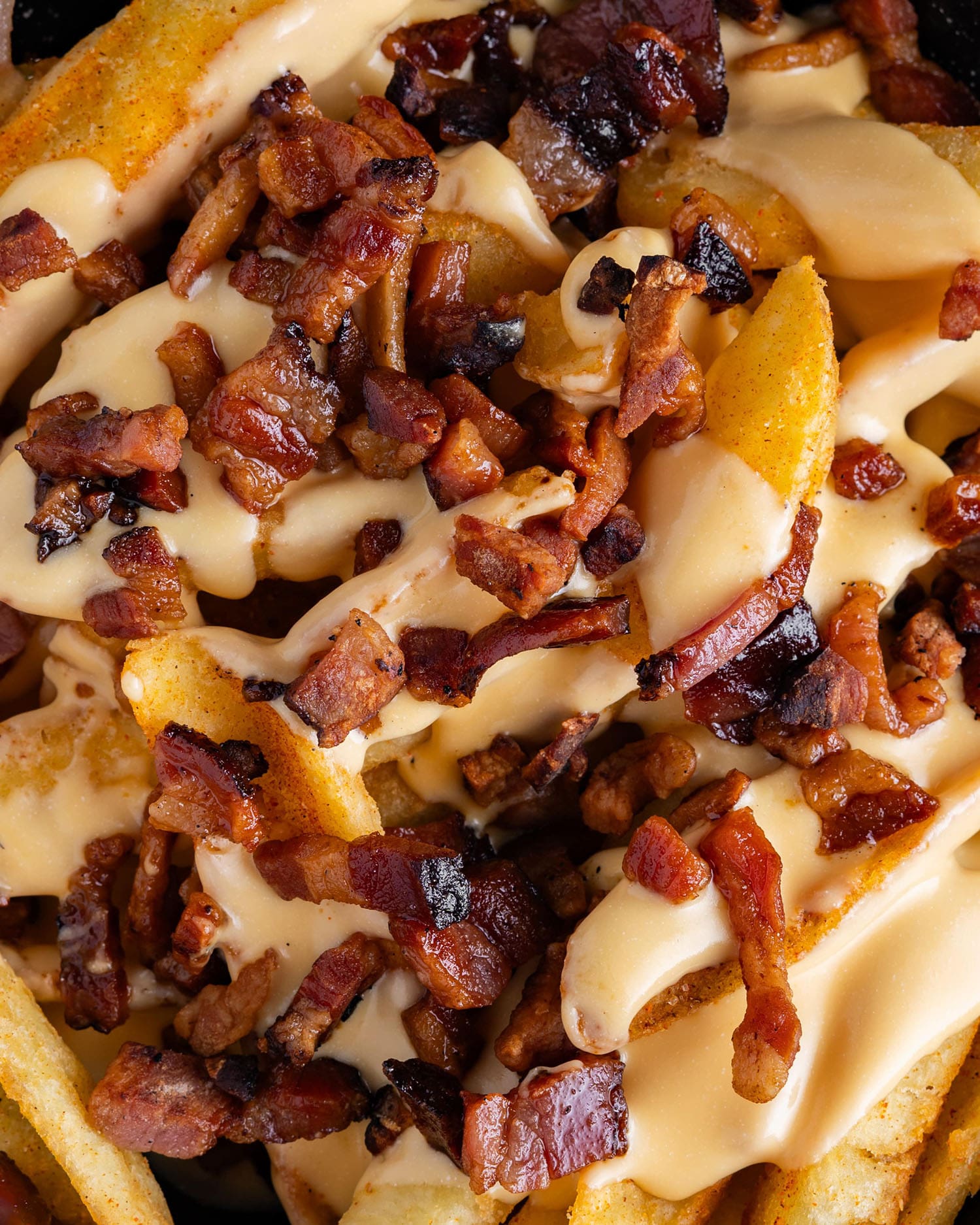 Loaded fries topped with bacon and melted cheese sauce at Klüg Burgers