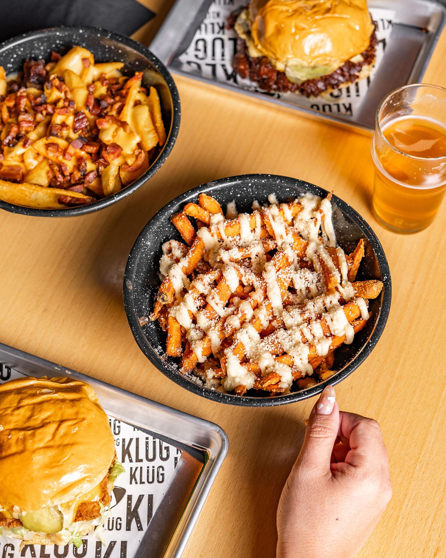 A spread of starters and loaded fries bowls at Klüg Burgers