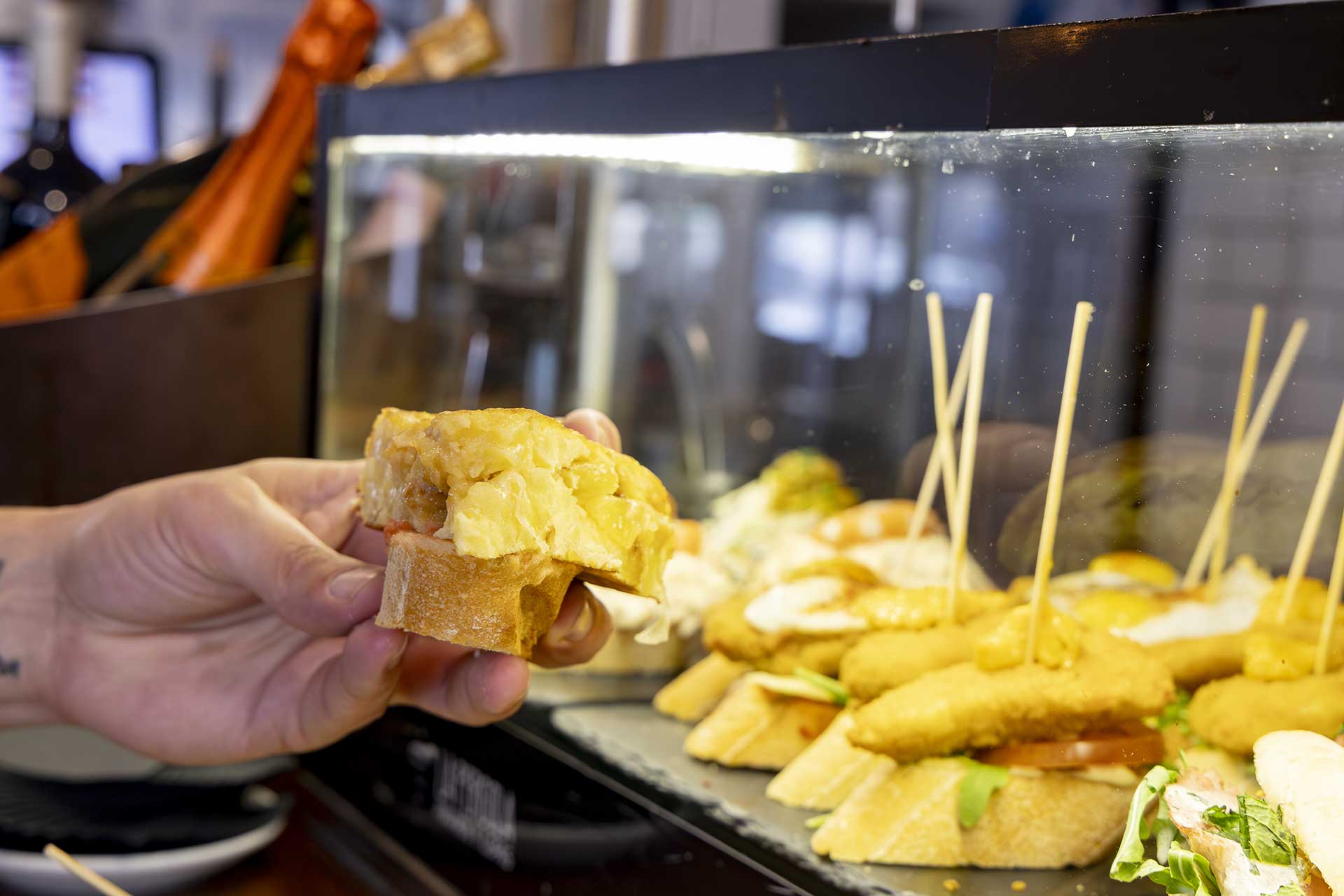 Hand holding a slice of Spanish tortilla on bread
