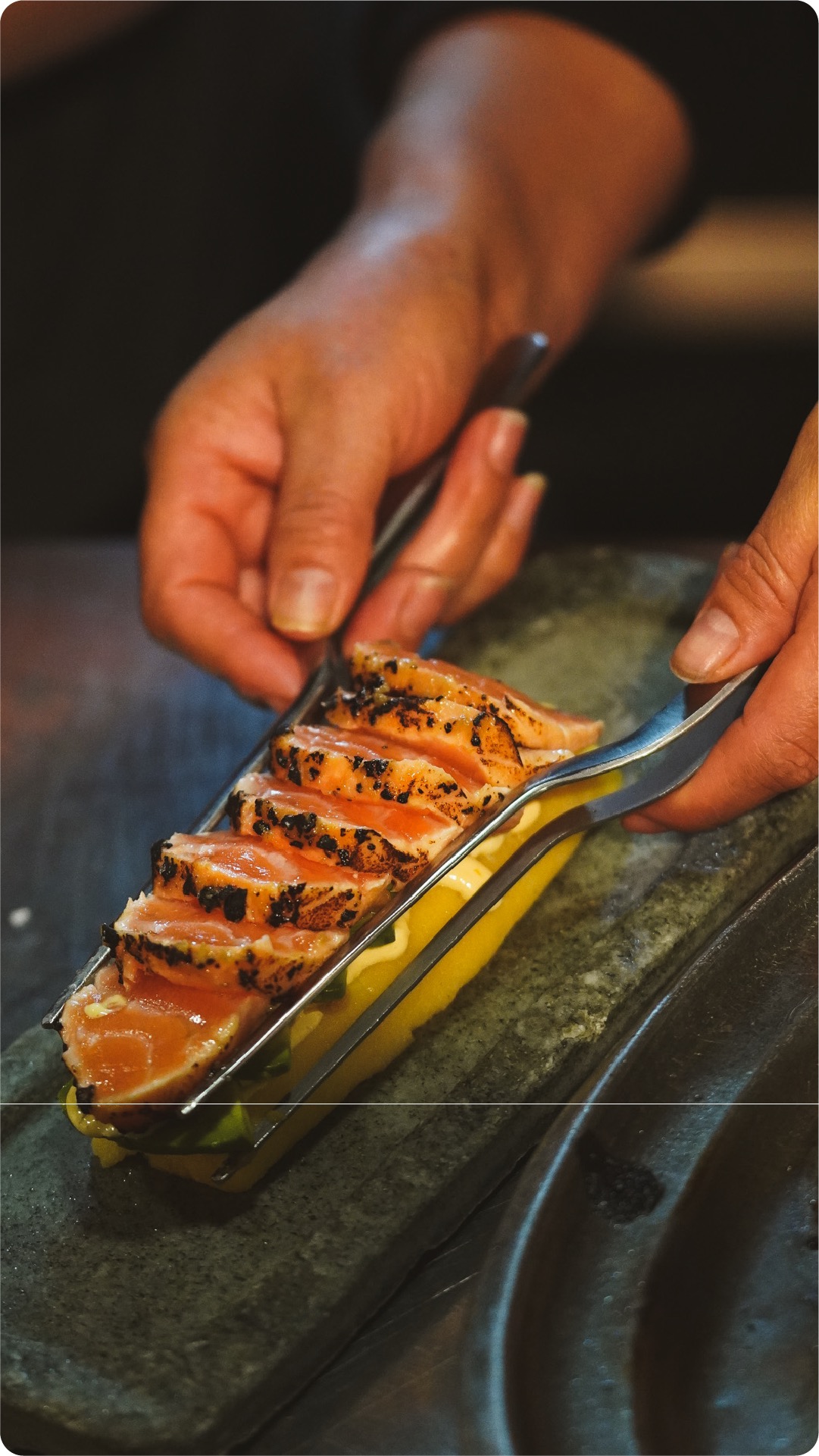 Seared salmon maki-causa being plated over avocado puree