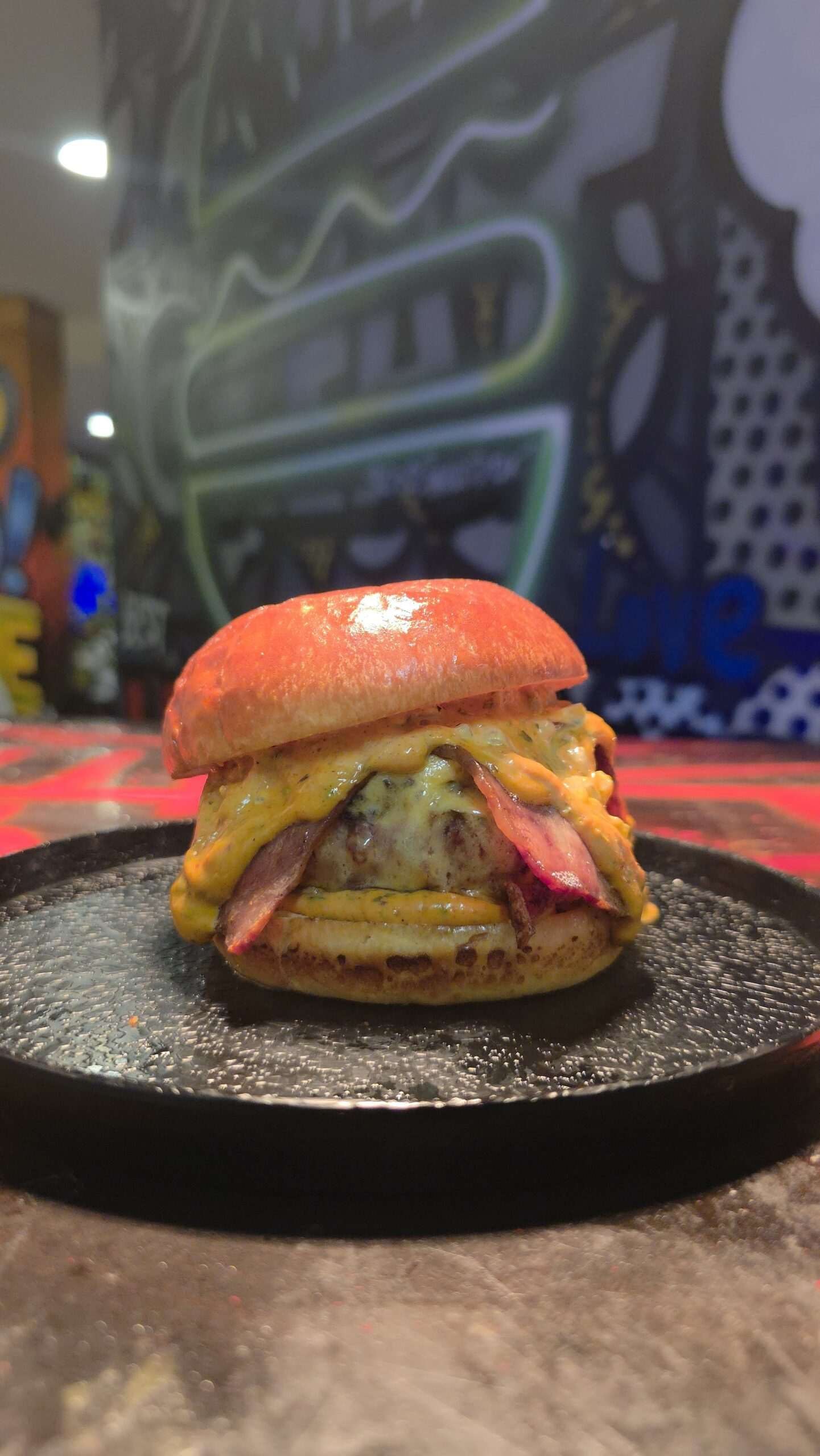 A smash burger on a black plate at Sexto Sentido, Palma
