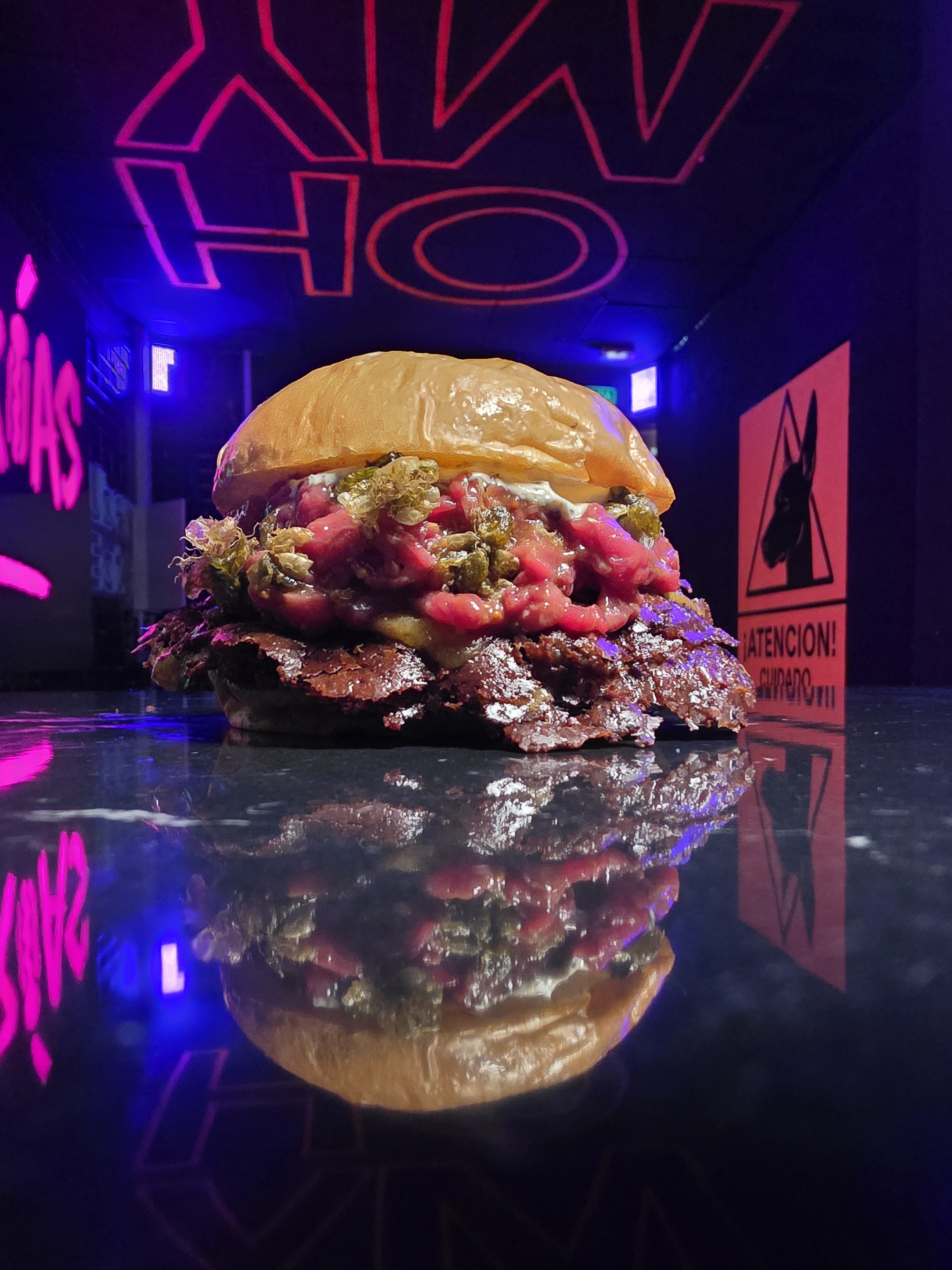 A loaded smash burger on the counter at Sexto Sentido
