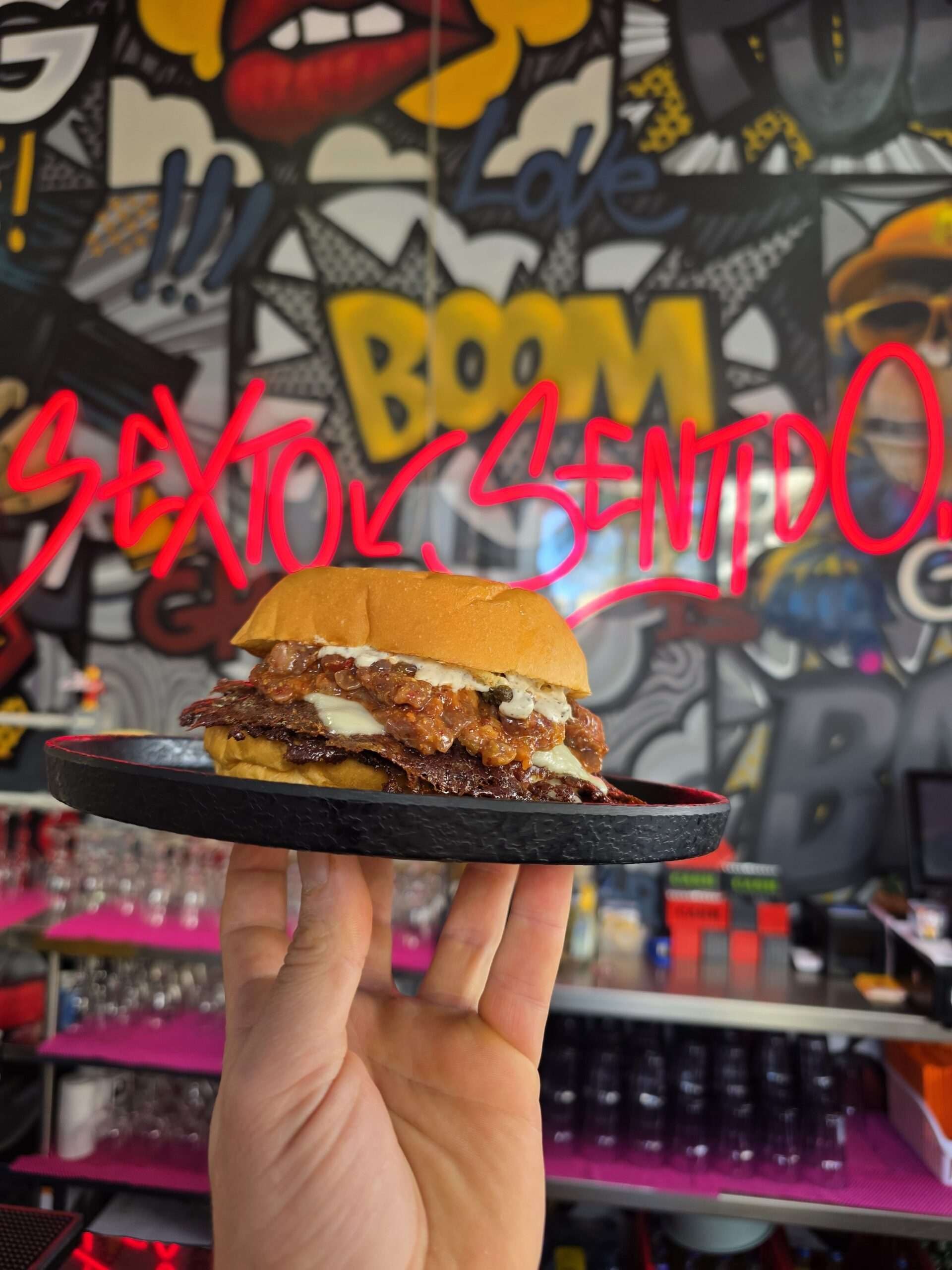 A smash burger held on a plate at Sexto Sentido
